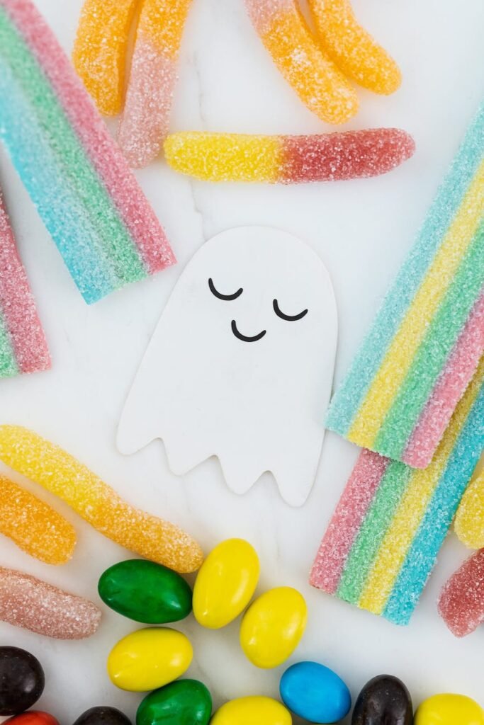 lots of candies scattered around a cute ghost paper cutout